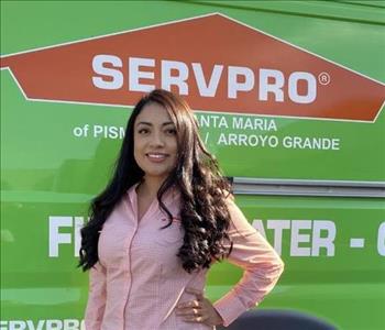 Female smiling with light orange shirt, green SERVPRO van in background 