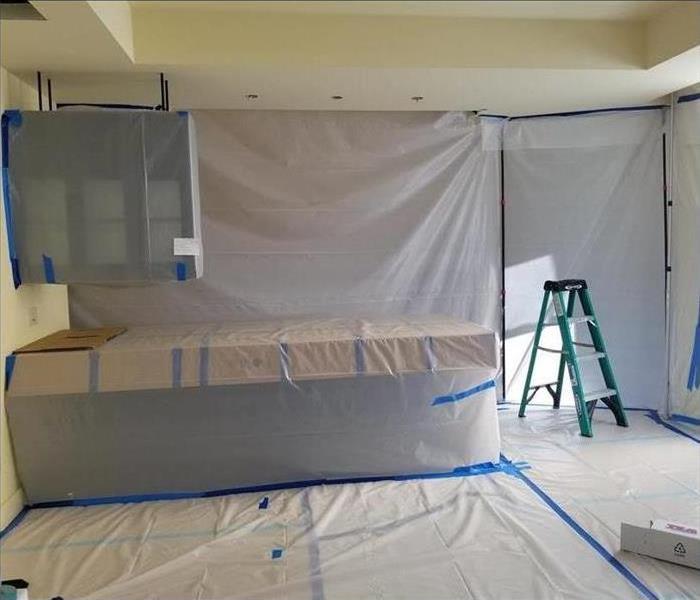 cabinets covered with plastic and blue tape 